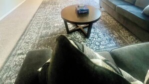 Ein modernes Wohnzimmer mit einer Couch, einem Couchtisch und Blick auf die Küche und den Essbereich.