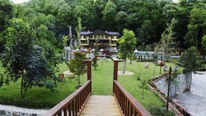 A wooden deck leading to a large, multi-story building surrounded by lush greenery and a pool area. - Casa Giallo Managed By Dedeman (Sapanca)