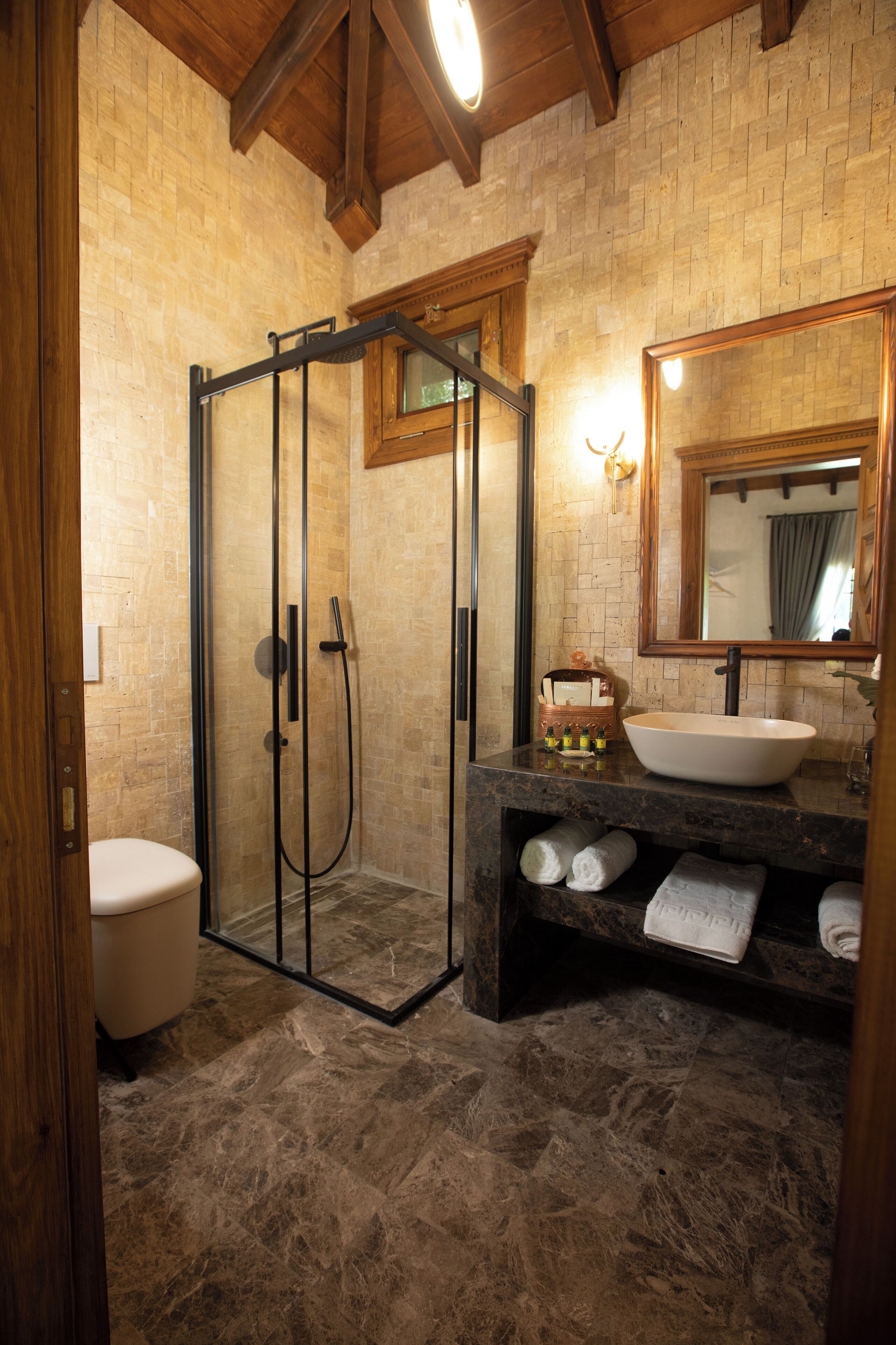 A bathroom with a glass-enclosed shower, a sink with a mirror above, and a towel rack with towels.