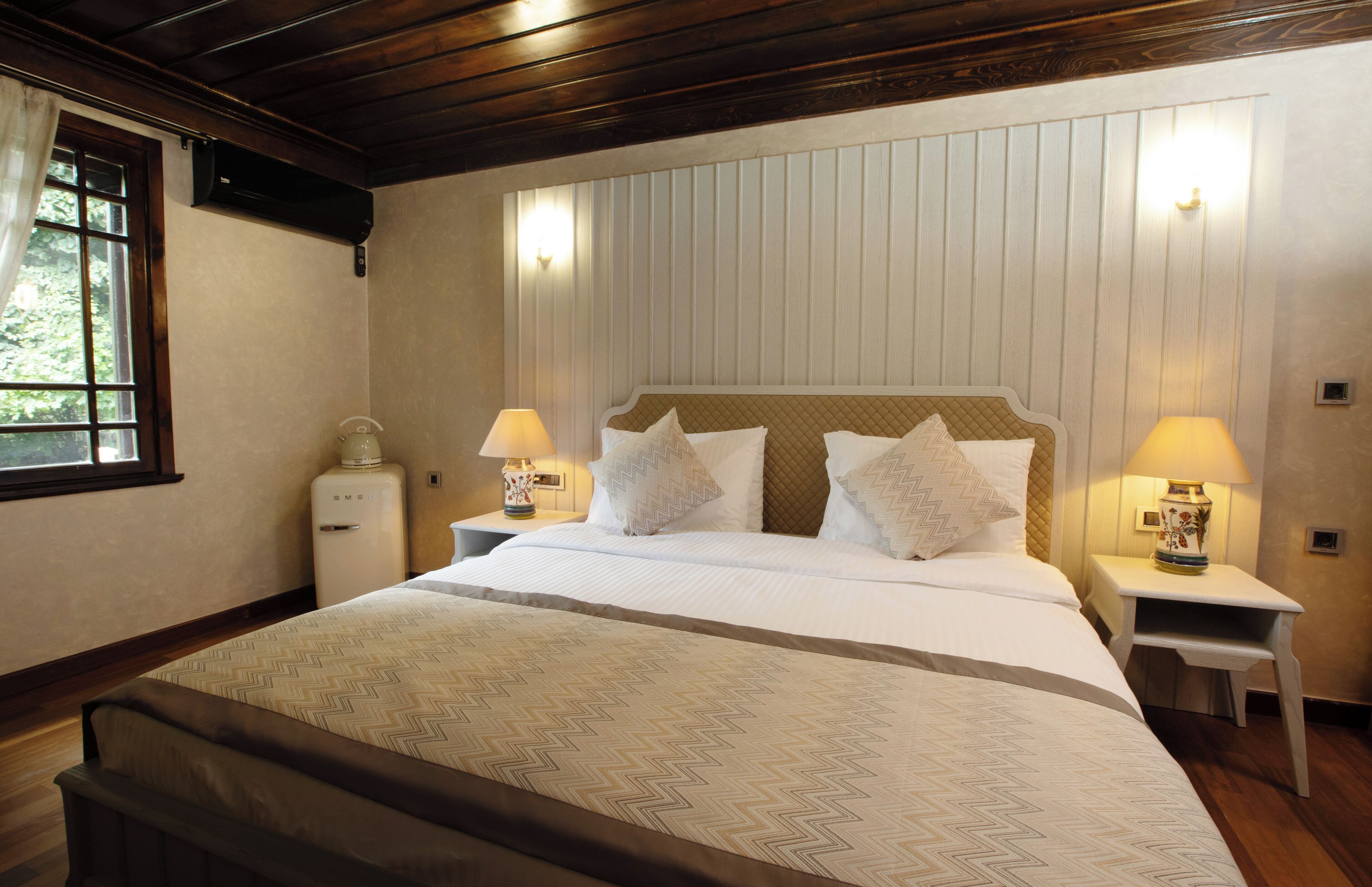 Un dormitorio con una cama grande, dos mesitas de noche con lámparas, un aparador y un calentador fijado a la pared.