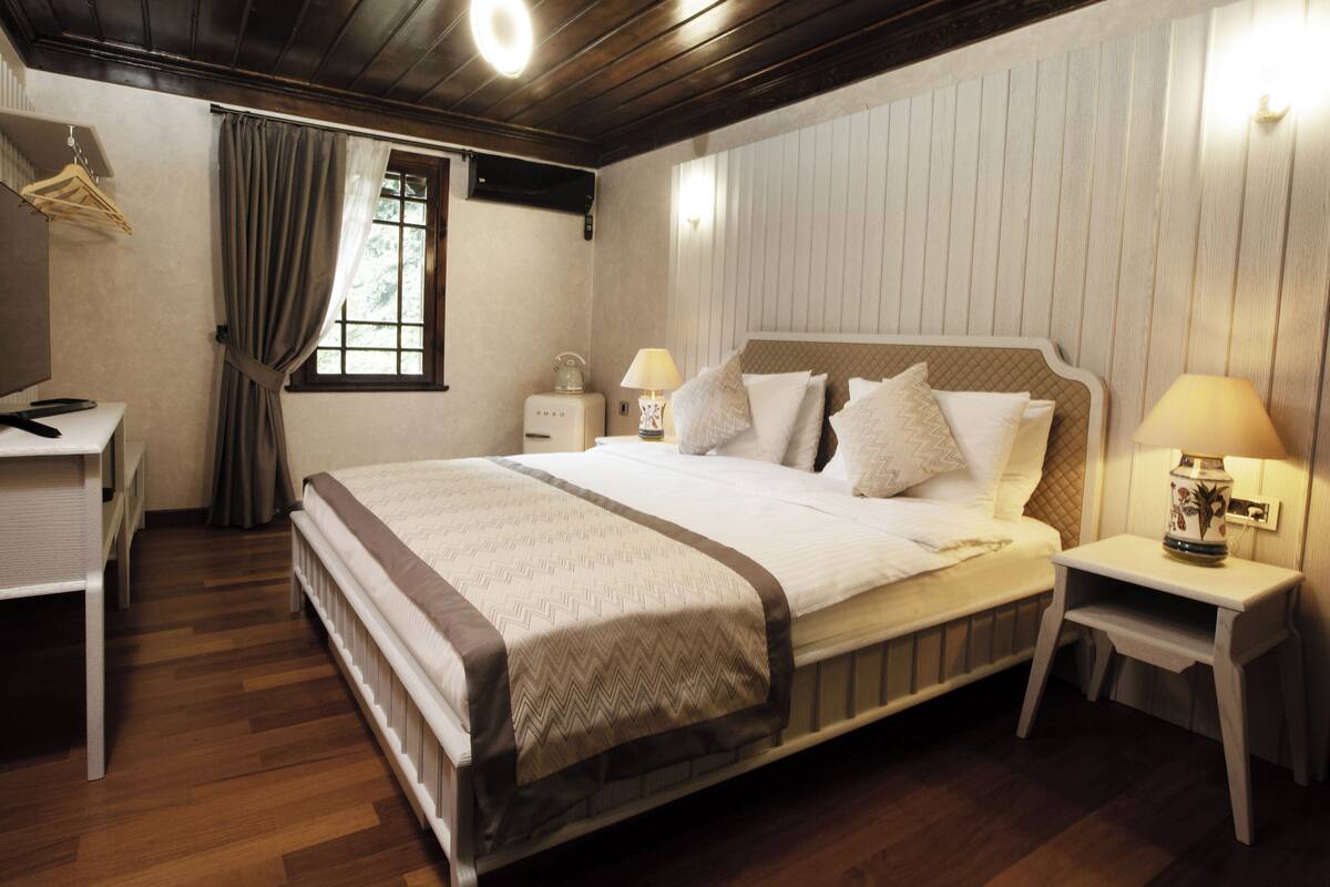 A bedroom with a bed, bedside tables, a desk, and a hanging clothes rack.