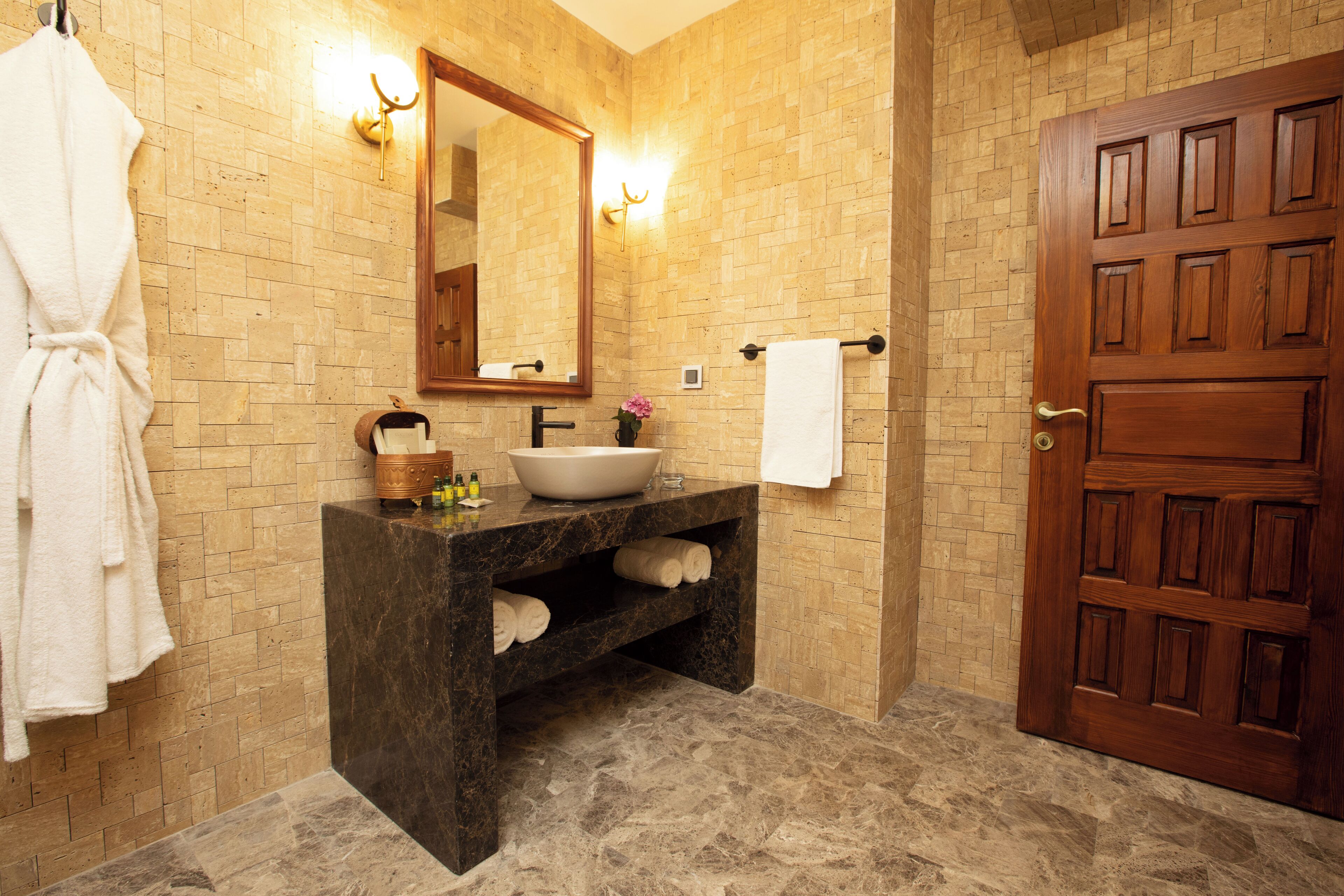 A bathroom with a marble sink, a wooden door, and a towel rack.