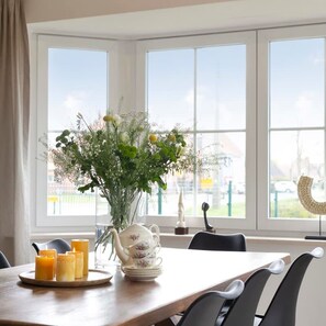 A dining area with a table set for four, a vase of flowers, a teapot, and candles. - Family House With a Beautiful View in Damme (Bruges)
