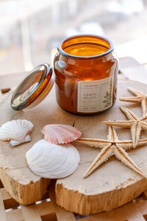 A scented candle labeled "LEMON GRASS" on a wooden surface with seashells and a starfish. - Cosy Flat With Lateral sea View (Middelkerke)