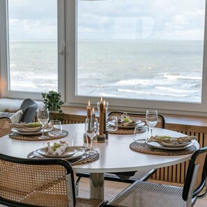 Enjoy a romantic meal with a view of the ocean from this dining area, featuring a round table and wicker chairs.