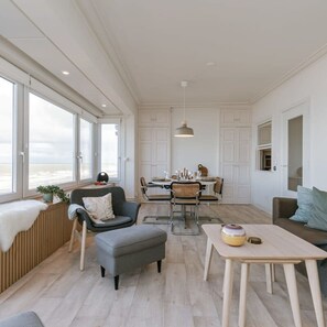 Enjoy a spacious room with a high ceiling, large windows, and a central dining area.