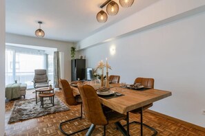 A modern dining area with a wooden table, leather chairs, and pendant lighting. - Characterful Apartment With Lateral sea View (Middelkerke)