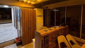 A room with a wooden bar and chairs, a large window, and a door leading outside. - hotel budapest (Seferihisar)