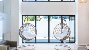 Un interior moderno con dos sillones colgantes, un sofá y una mesa redonda.