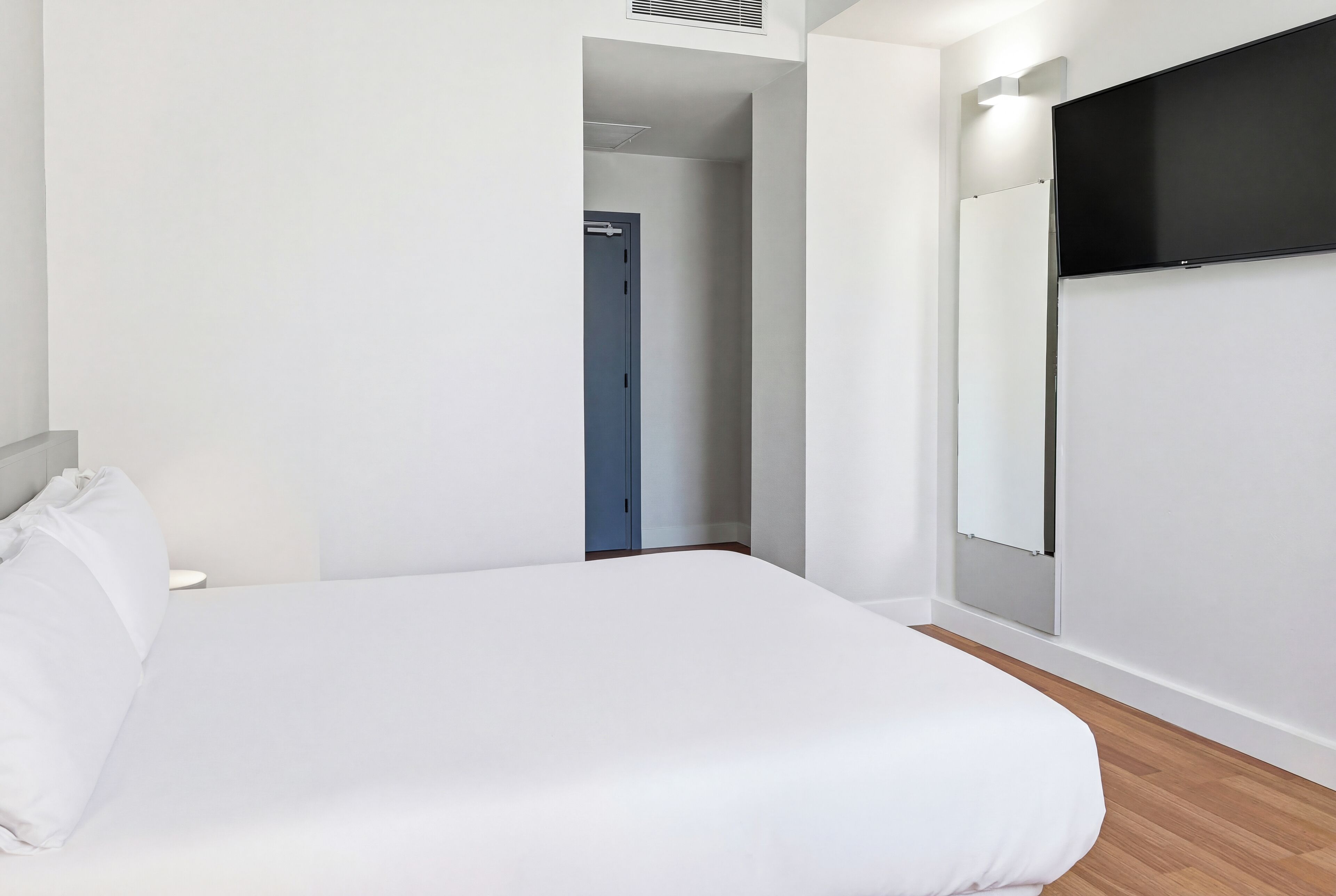 Une chambre à coucher comprenant un lit, une armoire et une porte donnant sur une autre pièce.