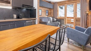 A modern kitchen with dark cabinets, a wooden dining table, and bar stools.