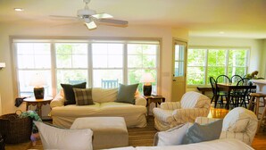 A spacious living room with a large sofa, a striped armchair, and a dining area with a table and chairs.