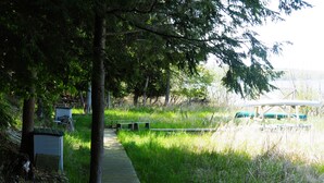 A wooden pathway leading through a park with benches and a green structure in the background.