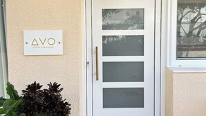 Una puerta blanca con un panel de vidrio satinado, una planta pequeña en maceta y un letrero que dice "AVO LUXURY APARTMENT".