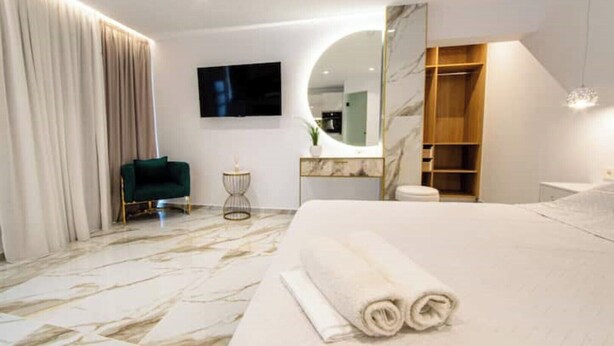 Un dormitorio moderno con una cama grande, televisor, espejo y vestidor.