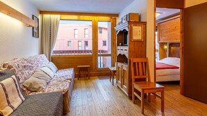 Una habitación acogedora con una cama, un sofá, un armario de madera y una pequeña mesa.
