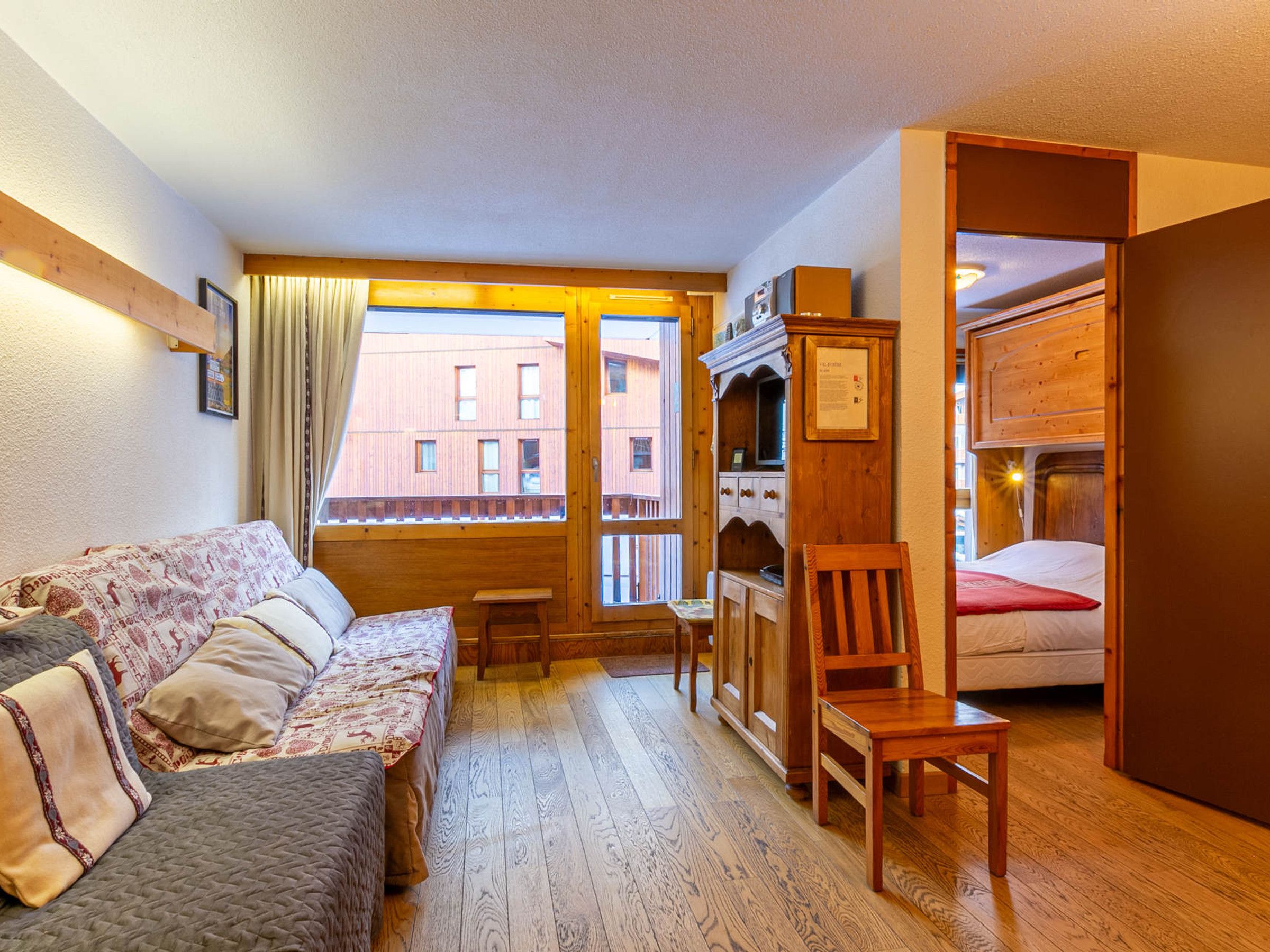 A cozy room with a bed, a sofa, a wooden cabinet, and a small table.