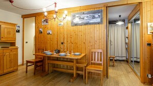 Un comedor de madera con una mesa dispuesta para cuatro, armarios de madera y una araña.