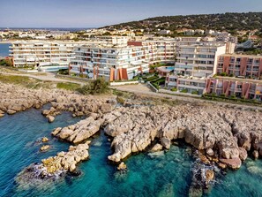 Un hotel frente al mar con varias edificaciones, costa rocosa y aguas azul turquesa.