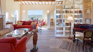 A spacious living room with a red sofa, a wooden coffee table, and a bookshelf filled with books.