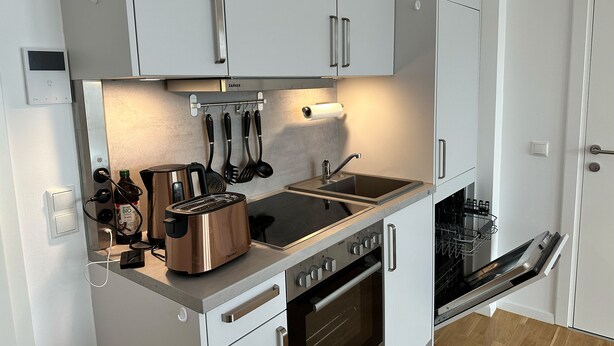 A compact kitchen with white cabinets, a built-in oven, a toaster, and a sink. - Modernes Apartment I Parkplatz I Terrasse I Sehr Beliebt bei Wanderer (Blumberg)