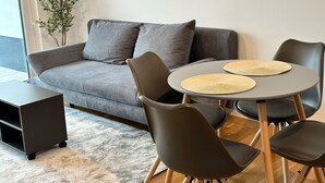 A modern living room with a grey sofa, two black chairs, a small round table with woven placemats, and a plant in the corner. - Modernes Apartment I Parkplatz I Terrasse I Sehr Beliebt bei Wanderer (Blumberg)
