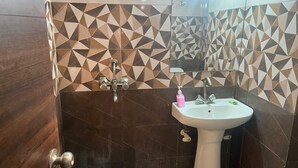 Un baño con un lavamanos blanco, un espejo y baldosas con un estampado geométrico.