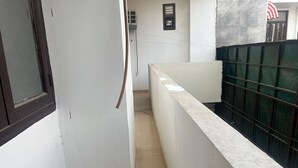 Un pasillo estrecho con una pared blanca, suelo de madera y barandilla de metal en un lateral.