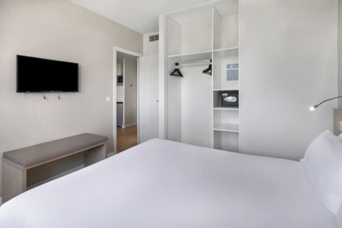 Un dormitorio con cama, banca, televisor, armario y closet.