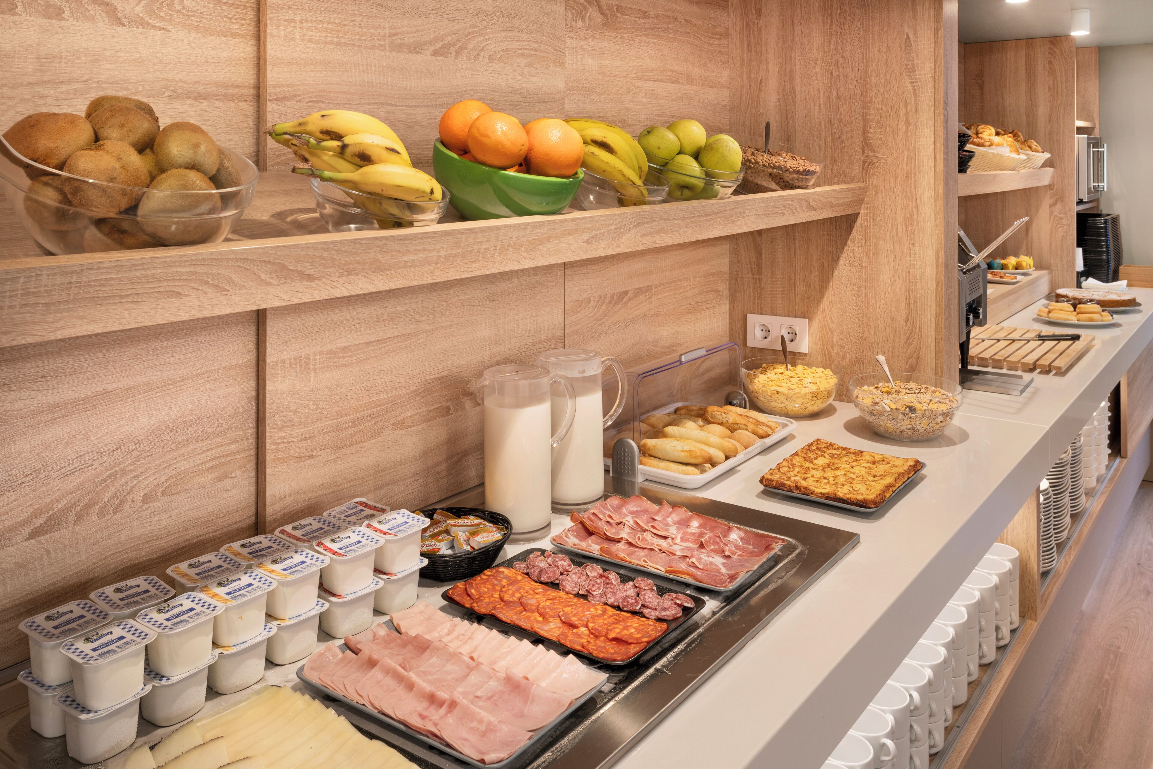 Un bufé con diversos alimentos, entre ellos frutas, productos lácteos y carnes.