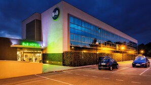 Un hotel tipo bed and breakfast con fachada moderna, amplias ventanas y un estacionamiento con automóviles.