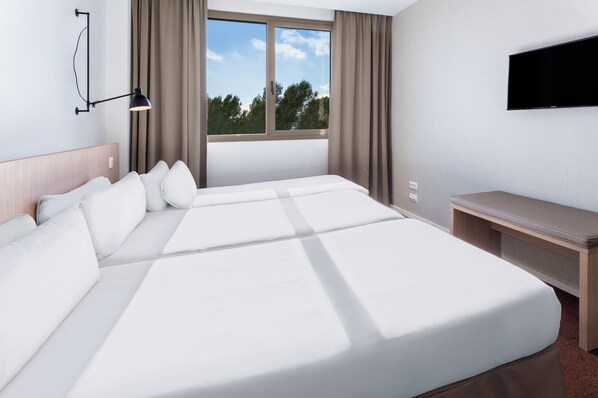 A hotel room with a large bed, a desk, a flat-screen TV, and a window with curtains.