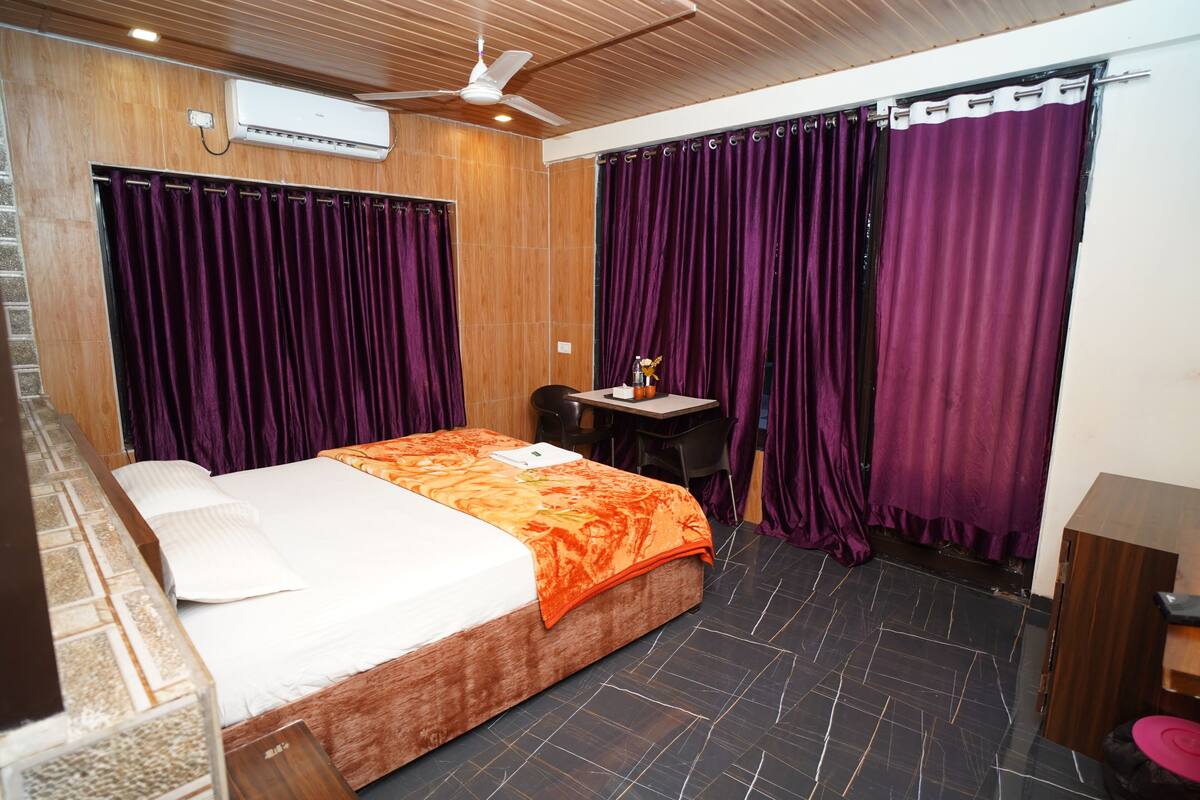 Habitación de hotel con una cama, un escritorio y cortinas moradas.