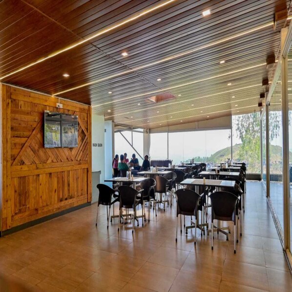 Un espace de restauration moderne avec des murs en bois et une vue sur un groupe de personnes à l’extérieur.