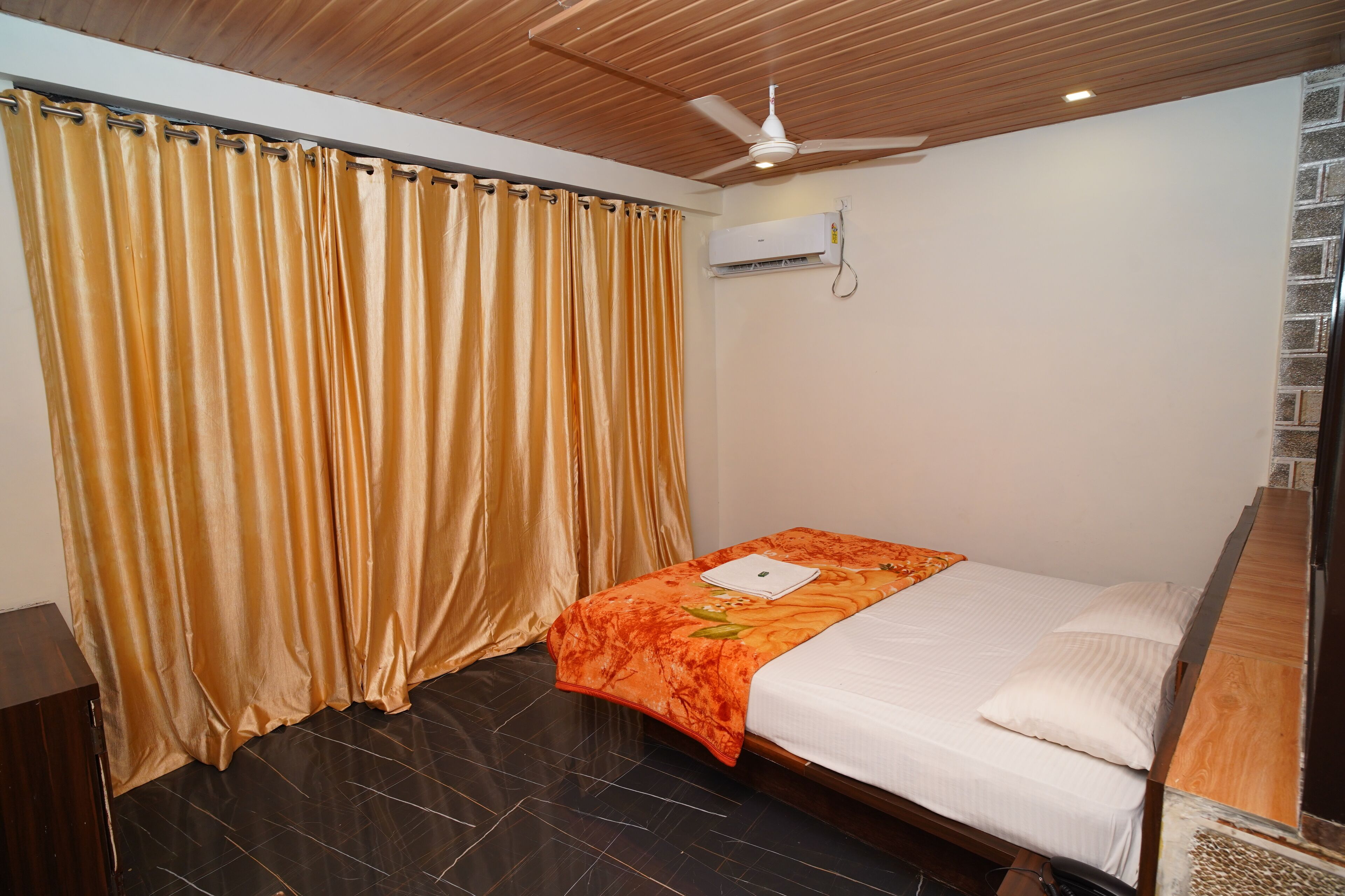 A bedroom with a bed, curtains, a ceiling fan, and an air conditioning unit.