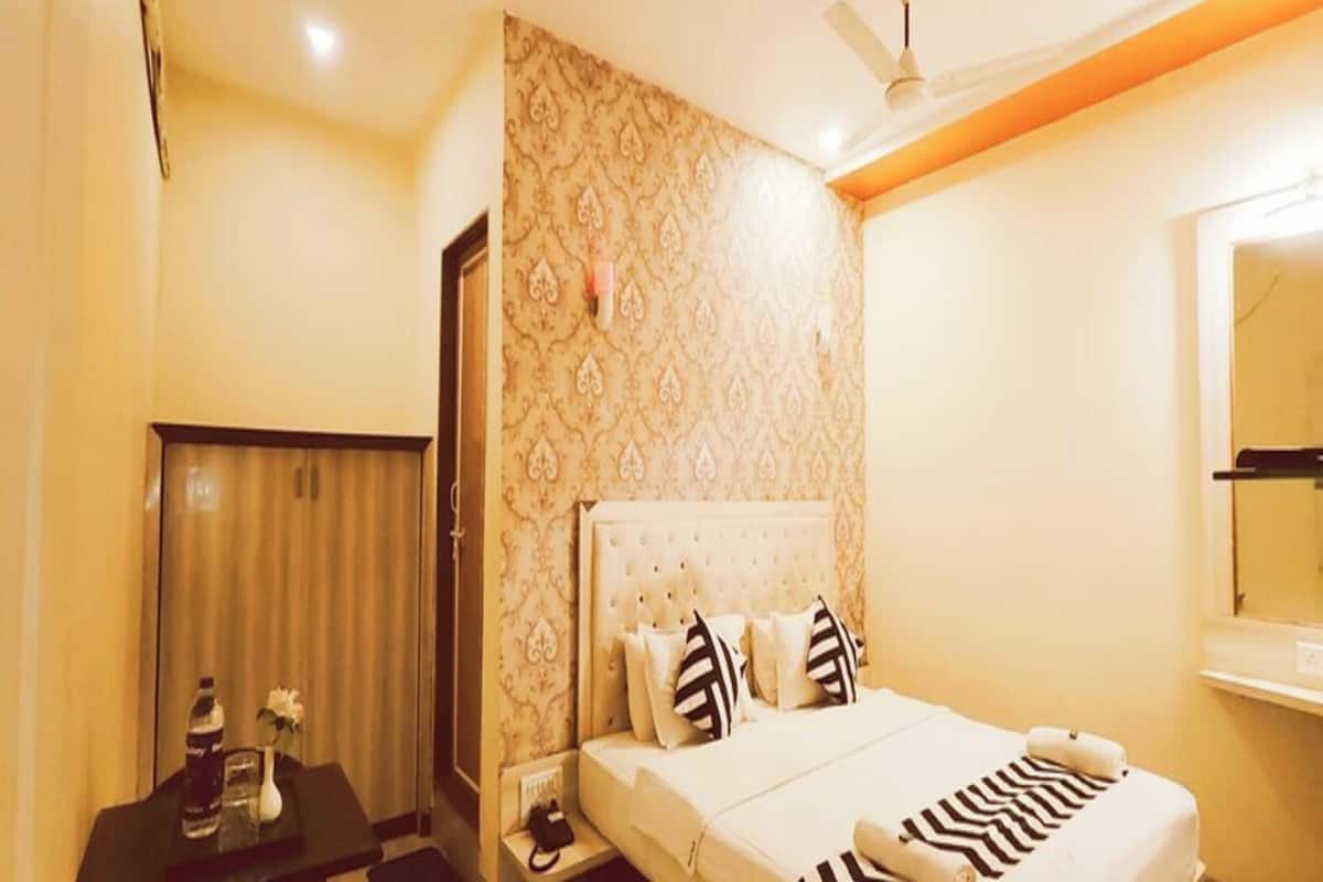 Una habitación de hotel con cama, mesita de noche y espejo.