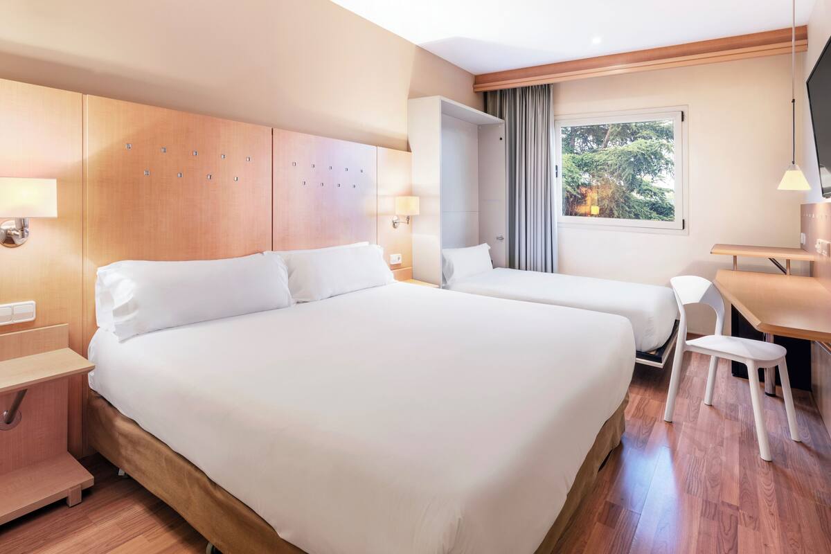 Habitación de hotel con dos camas, un escritorio y una silla.