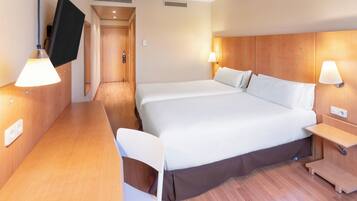 A hotel room with a large bed, bedside tables, a desk, and a TV mounted on the wall.