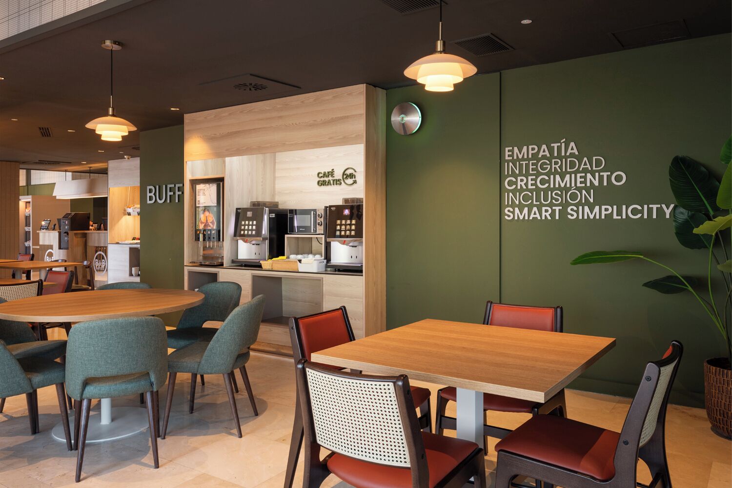 A modern cafe with wooden tables and chairs, a coffee machine, and a wall with motivational text.