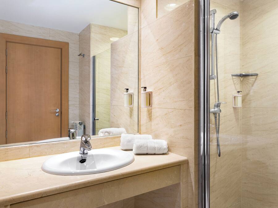 A modern bathroom with a sink, mirror, and glass-enclosed shower.