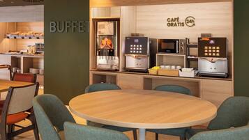 Un área de café con mostrador de buffet, una máquina de café y asientos.