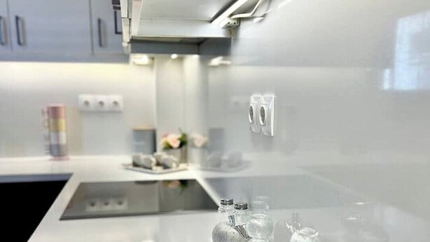 A modern kitchen with a white countertop, stainless steel appliances, and a glass display case with bottles and glasses. - Marble Luxury Villa in Neapolis (Αγιος Νικολαος)