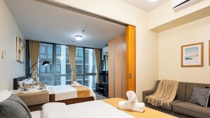 Ett hotellrum med två sängar, en soffa, ett skrivbord och en TV.