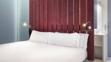 Un dormitorio moderno con una cama grande, panel de pared de madera, mesitas de noche e iluminación empotrada.