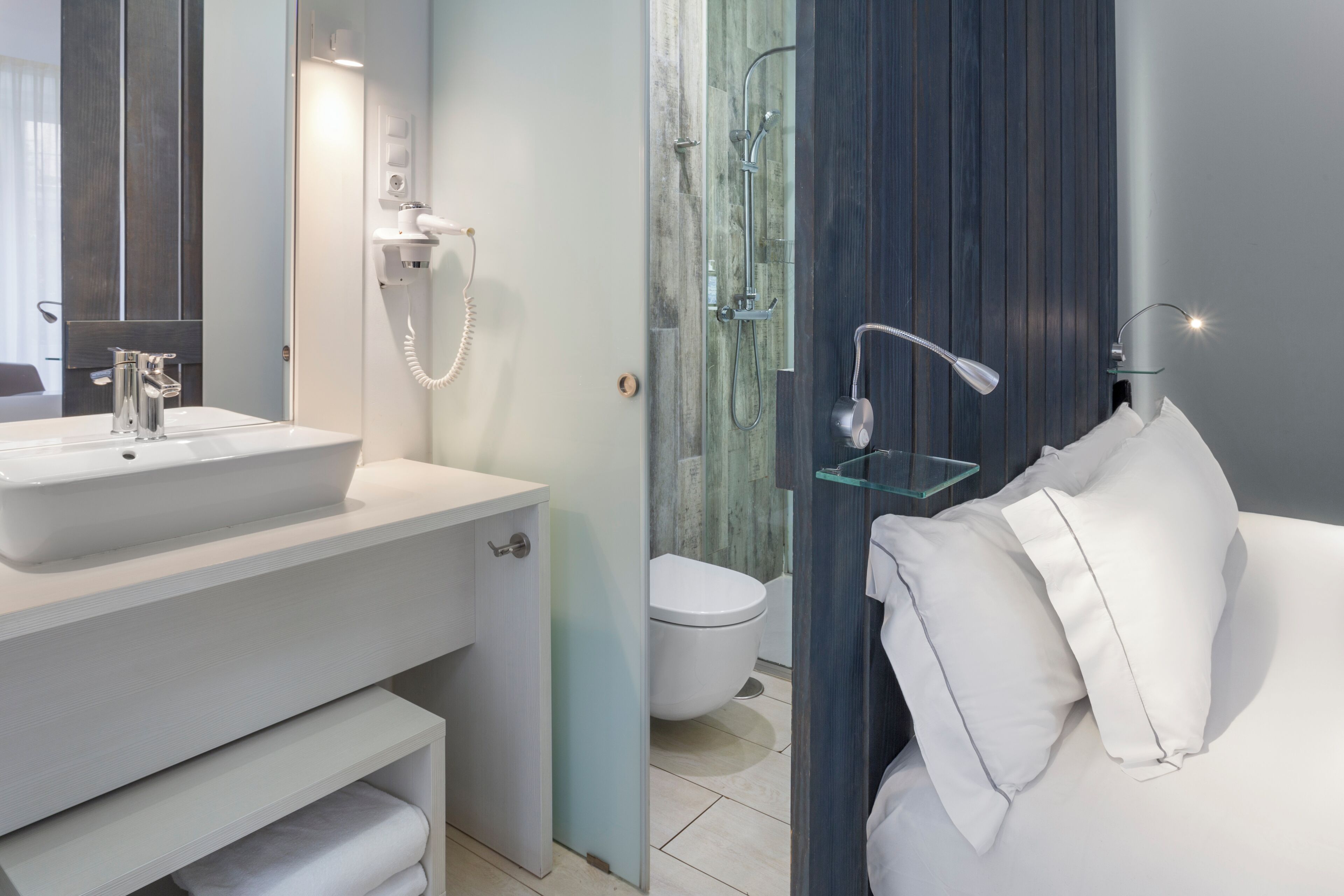 A modern bathroom with a white sink, a glass shower enclosure, and a white toilet.