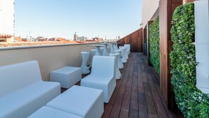 Une terrasse sur le toit dotée de sièges rembourrés blancs et d’un mur végétal vertical.