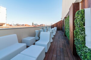 Une terrasse sur le toit dotée de sièges rembourrés blancs et d’un mur végétal vertical.