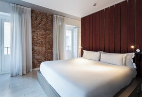 Une chambre moderne avec un grand lit, un mur en briques et un mur recouvert de panneaux en bois.