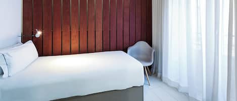 A modern bedroom with a bed, a chair, and a wooden wall panel.