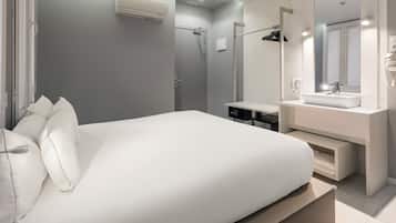 Ein modernes Schlafzimmer mit einem großen Bett, einem begehbaren Kleiderschrank, einem Badezimmer mit Waschtisch und Spiegel sowie einer Dusche.